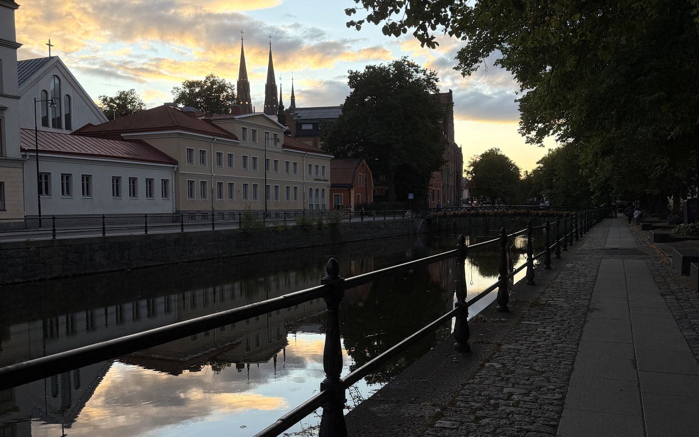 Fyrisån i centrala Uppsala i kvällsljus, med Uppsala domkyrkas torn i fonden